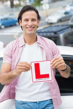 Learner driver smiling and holding l plate Stock Photos