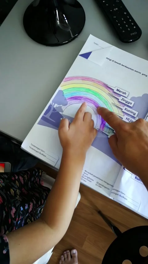 Learning about rainbows in the Malay language, the toddler points at the book. Stock Footage 324890615
