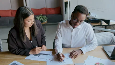 Learning to analyze trading charts in an office with a girl from India and a Stock Footage 335732319