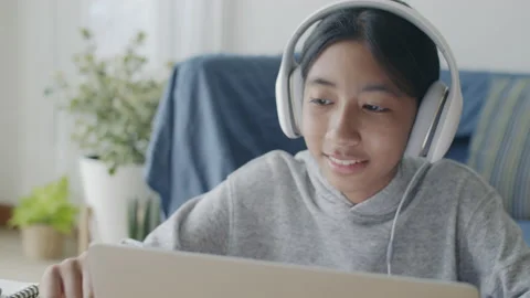 Learning. Asian girl is studying using laptop with headset in morning. Stock Footage 141745884
