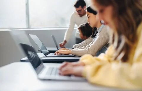 Learning to code with confidence: Male teacher helping children master prog.. Foto stock