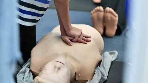 Learning CPR techniques for first aid on a resuscitation mannequin during 스톡 동영상 323320565