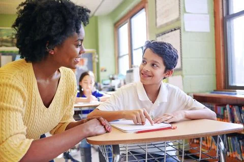 Learning, education and teacher help student with assignment in elementary Stock Photos