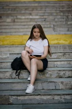 Learning female student preparing for graduation outdoors in summer. Stock Photos
