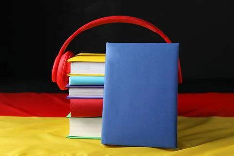 Learning foreign language. Different books and headphones on flag of Germany Stock Photos
