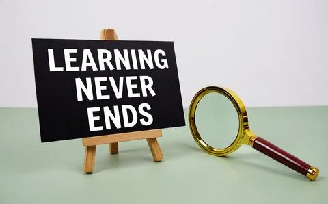 Learning never ends text on paper card with magnifying glass on green backg.. Stock Photos