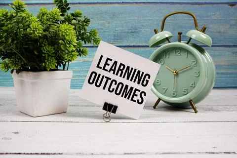 Learning Outcomes text written on paper card with alarm clock on wooden bac.. Stock Photos
