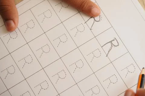 Learning to write letters with pencil on a practice sheet Stock Photos