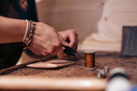 Leather artisan cutting thread for sewing handmade leather goods Stock Photos