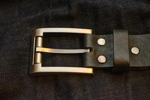 Leather belt with simple rectangular iron buckle on dark blue denim jeans Stock Photos