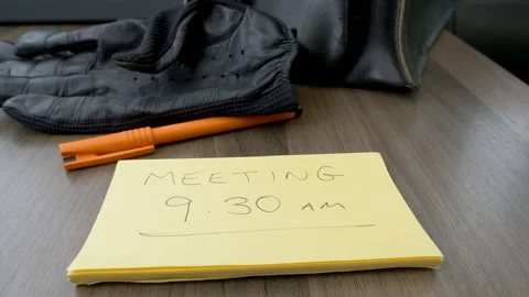 Leather briefcase and gloves placed on office desk with message about meeting. Video stock 142264978
