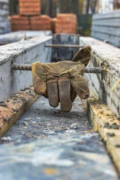 Leather construction gloves on the concrete surface of the foundation. Old wo Stock Photos
