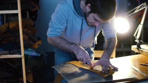 Leather craft or leather working. strong man's hands is cutting piece of skin Stock Footage 71389038