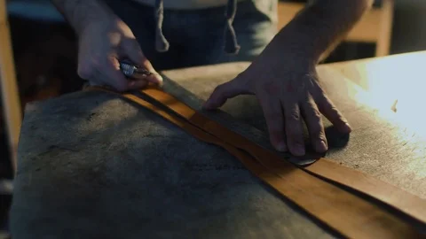 Leather craft or leather working. strong man's hands is cutting piece of skin Stock-Footage 71389118