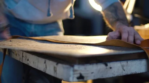 Leather craft or leather working. strong man's hands is cutting piece of skin Stock Footage 71389259