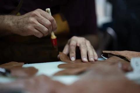 Leather craft in progress: close-up of hands shaping leather pieces with a tool Stock Photos