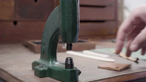 Leather craft workshop, man applies a rivet with a small press Stock Footage 132340225