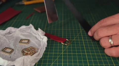 Leather craftsman attaching metal ring to red leather strip Video stock 311529892