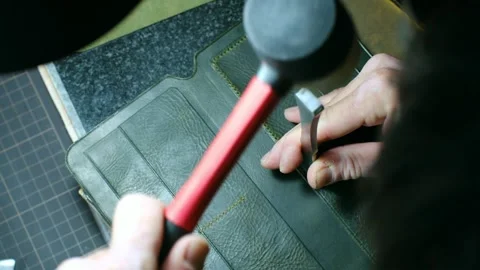 Leather craftsman making wallet using hammer striking stitching chisel Stock-Footage 296747763