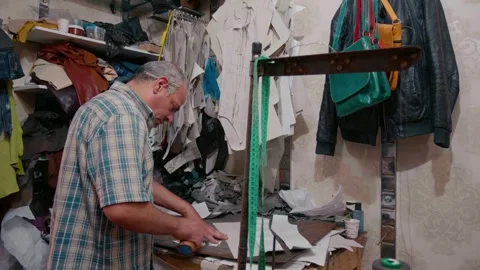 Leather craftsman working in his studio surrounded by leather patches. Vídeos de archivo 296375886