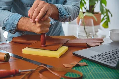 Leather craftsman working leather using stamp in his workshop Stock Photos