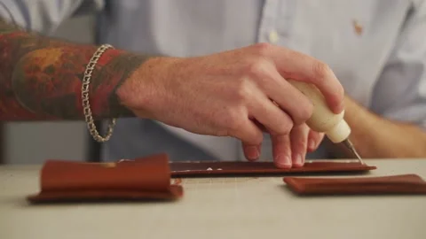 Leather craftsman works in a workshop. Master making leather wallet. Man applies Video stock 199295364