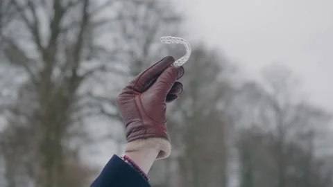 Leather glove hand showcasing a clear aligner for teeth regulation, winter Stock Footage 258553274