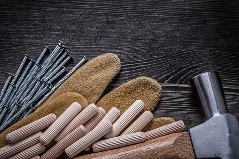 Leather gloves stainless construction nails claw hammer wooden dowels. Stock Photos