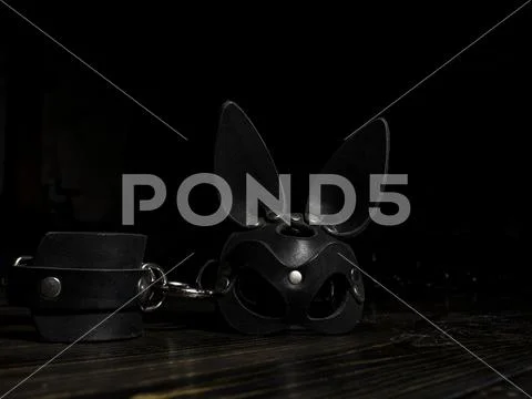 Leather handcuffs and a bunny mask on a wooden table. toys for adults. fetish Stock Photos