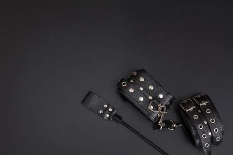 Leather handcuffs and stack for bdsm games on black background Stock Photos