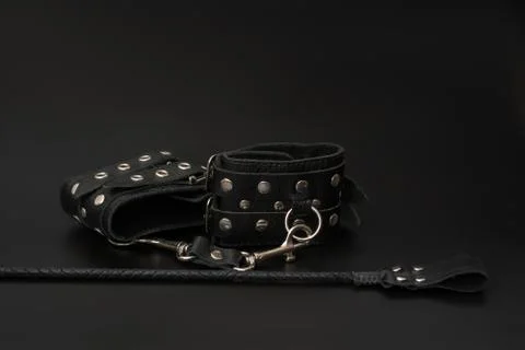 Leather handcuffs and stack for BDSM games on black background Stock Photos