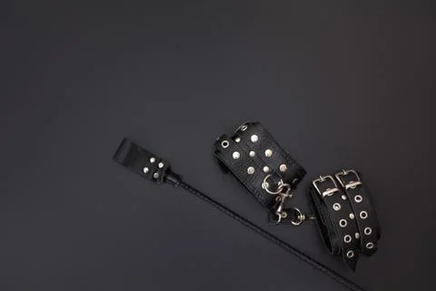 Leather handcuffs and stack for bdsm games on black background Stock Photos