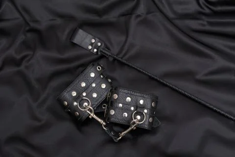 Leather handcuffs and stack on black background. Accessories for adult Stock Photos