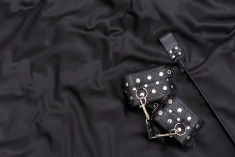 Leather handcuffs and stack on black background Stock Photos