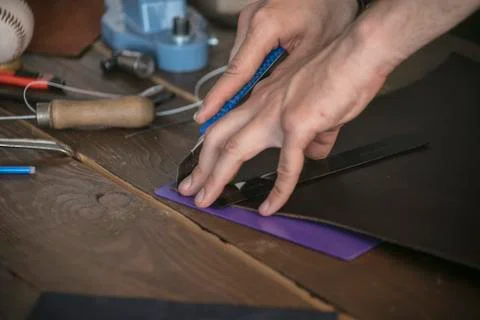 Leather maker cut leather with utility knife on special stand Stock Photos
