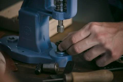Leather maker working with professional hand press on wooden table Stock Photos
