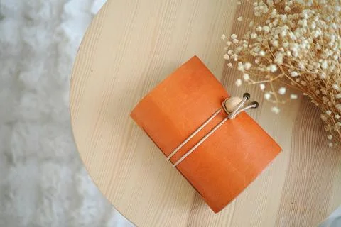 Leather notebook on a small wooden table with dried flowers Stock Photos