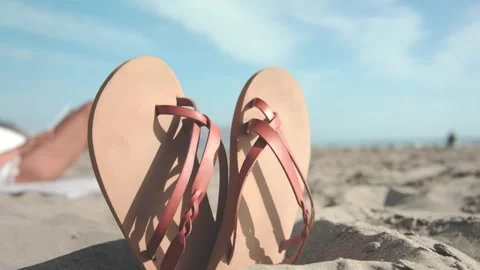 Leather sandals standing on the beach while relaxes reading a book Stock Footage 307428787