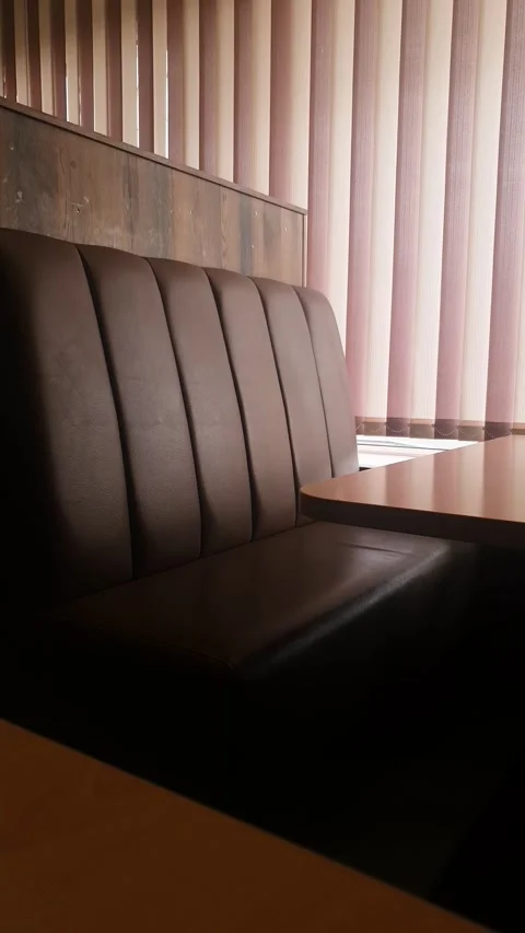 Leather seats and a table facing a window with blinds in cafe or diner vertical Stock-Footage 347820304