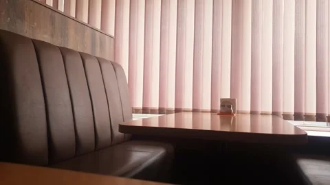 Leather seats and a table facing a window with blinds in a cafe or diner 스톡 동영상 347820318