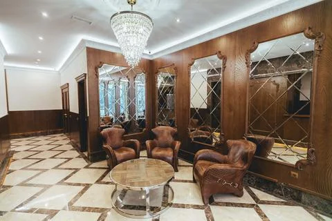 Leather sofas in the waiting room, mirrors and beautiful chandel Stock Photos