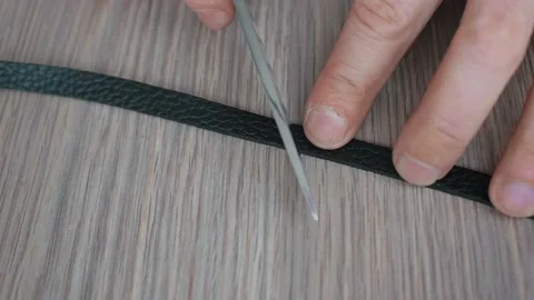 Leather worker cuts part of leather belt to make bracelet. Close up view of man Stock Footage 153201473