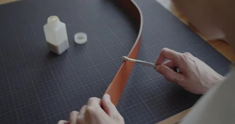 Leather worker dyeing edge of a leather belt during manufacturing process Stock Footage 144893470