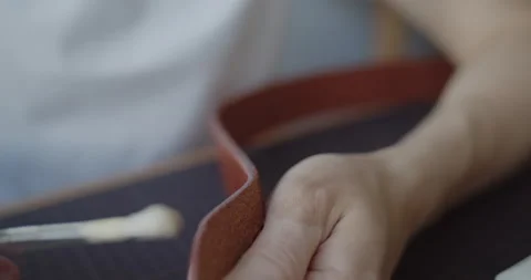 Leather worker dyeing edge of a leather belt during manufacturing process Stock Footage 146136138