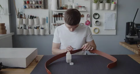 Leather worker dyeing edge of a leather belt during manufacturing process Stock Footage 146136565