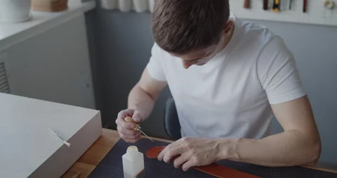 Leather worker dyeing edge of a leather belt during manufacturing process Stock Footage 146137250