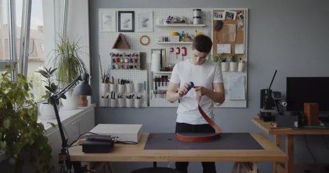 Leather worker grinding edge of a leather belt during manufacturing process Stock Footage 144893030