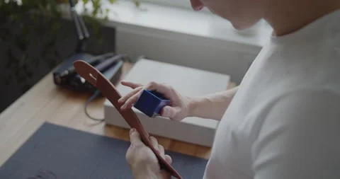 Leather worker grinding edge of a leather belt during manufacturing process Stock Footage 144893202