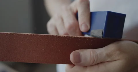 Leather worker grinding edge of a leather belt during manufacturing process Stock Footage 144893204