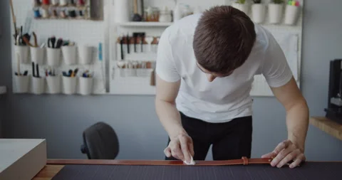 Leather worker oiling a leather belt during manufacturing process Stock Footage 146138667